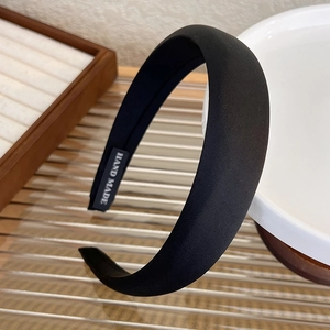 Detail view of handmade black satin headband with inner label on a ceramic bowl
