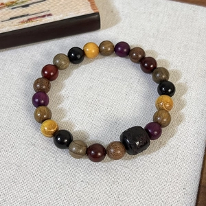 Détail macro des perles en bois de santal et cylindre gravé sur bracelet zen ethnique