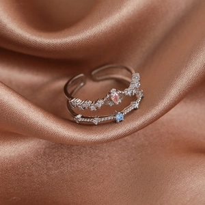 Close-up of double-layered silver ring with colorful zircon stones on brown silk