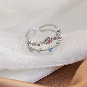 Macro shot of double-layer silver open ring featuring a heart-shaped stone and blue zircon