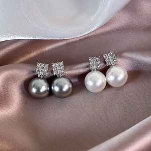 Detailed view of French sugar-cube pearl earrings with sparkling micro-set zircons on silk