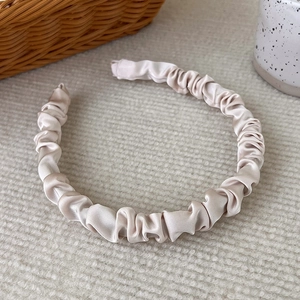 Detail shot of the champagne satin ruched headband with a premium silk texture