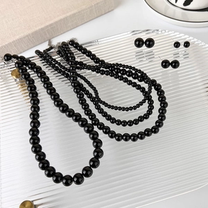 Detailed view of polished black bead necklace and earring set on decorative acrylic tray