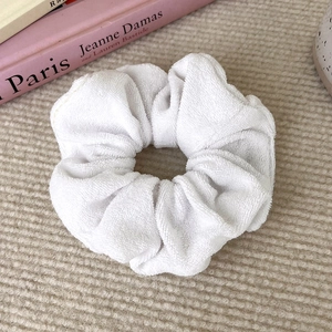 Detailed texture of white fluffy towel fabric scrunchie on a soft beige background