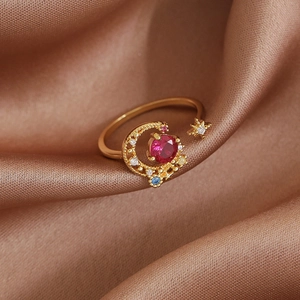 Detailed macro view of gold star and moon open ring with red stone on brown satin fabric