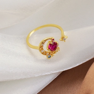 Close-up of gold moon and star ring with a red oval gemstone and multi-color zircons