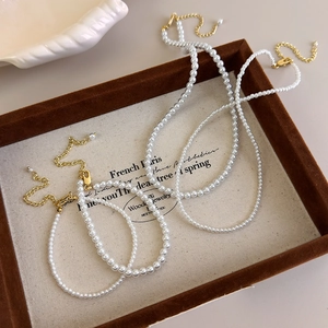 Elegant French style pearl necklace and bracelet set with gold clasps on a wooden tray