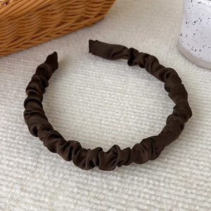 Close-up of pleated satin headband in dark brown with smooth fabric texture and finish