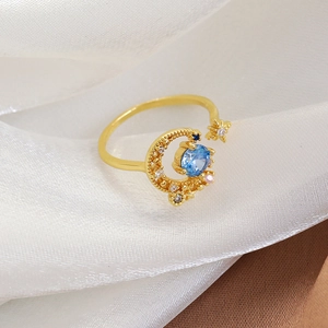 Macro shot of gold crescent moon and star open ring with blue cubic zirconia
