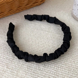 Macro view of black pleated satin headband showing rich texture and wavy fabric detail