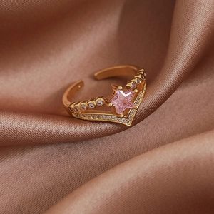 Detail of a golden open ring with a pink star gemstone and micro-pave crystals