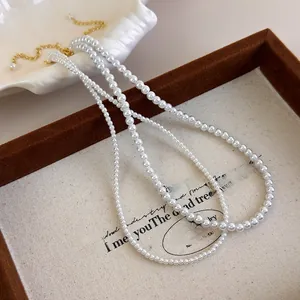 Detailed view of white faux pearl necklaces with elegant gold clasps on a canvas tray