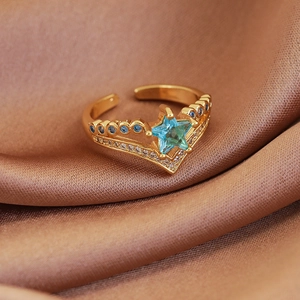 Macro shot of V-shaped gold crown ring with blue star zircon on satin fabric