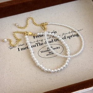 Detailed view of large and small white pearl bracelets with golden lobster clasps on a tray