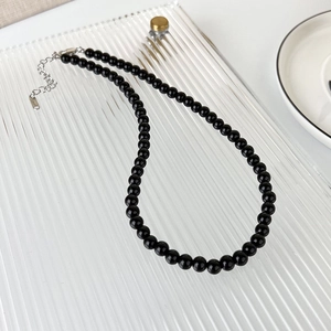 Detailed macro of black beaded necklace with silver stainless steel lobster clasp and chain