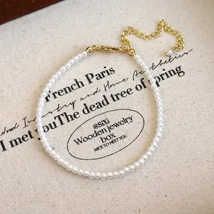 Close-up of elegant small white pearls with a golden lobster clasp and adjustable chain