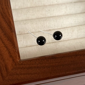 Macro view of S925 silver stamp on minimalist black bead earrings with glossy finish