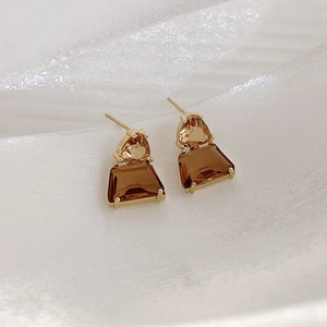 Detail of French style amber crystal earrings with golden claw setting on white silk