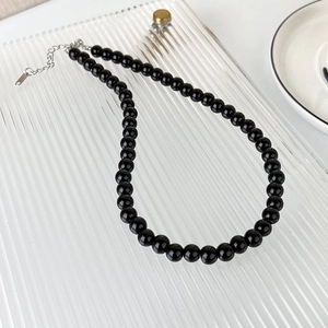 Close-up of black glass bead necklace with polished finish and silver lobster clasp