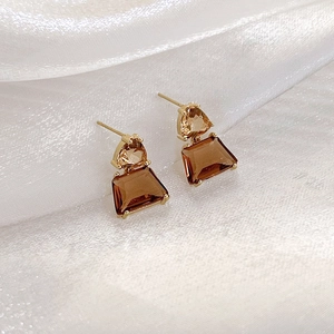 Detail view of French caramel crystal earrings with gold geometric stud and silk background