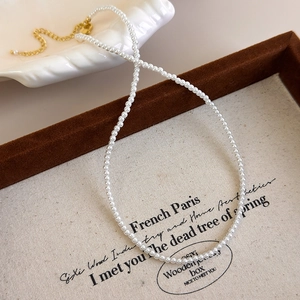 Detail of elegant pearl necklace with gold lobster clasp on a wooden jewelry display box