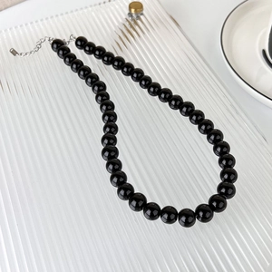Detail view of smooth black glass beads and S925 sterling silver lobster clasp on a necklace