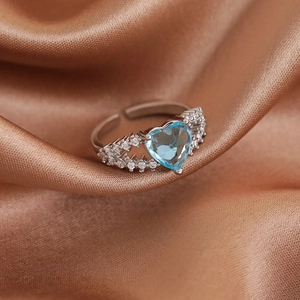 Macro shot of heart-shaped light blue gemstone ring with micro-pave side stones
