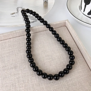 Detail of high-gloss black beaded necklace with adjustable silver lobster clasp and chain