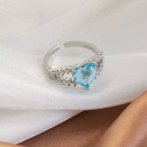 Macro shot of silver open ring with heart-shaped blue gemstone and pave zircon details