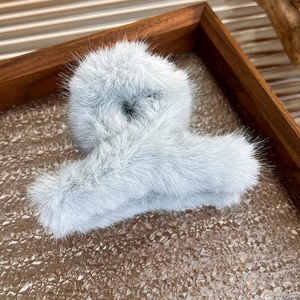 Close-up of fluffy light blue faux fur hair claw clip on a vintage wooden tray