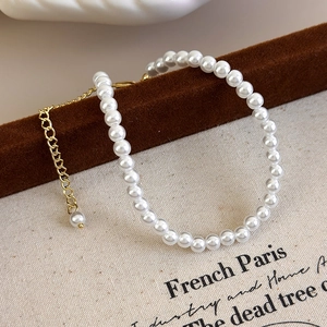 Detailed view of beaded pearl bracelet with gold adjustable chain on velvet display