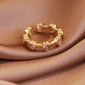 Macro detail of gold-plated open ring featuring pink heart-shaped crystal settings