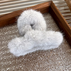 Close-up of light gray plush faux fur hair claw clip with a soft fluffy winter texture