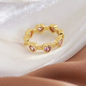 Macro shot of pink heart-shaped crystals on an adjustable 18K gold-plated ring band