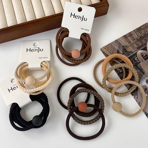 Detailed view of elastic hair bands in earthy tones with matte beads on white desk