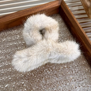 Close-up of soft white plush hair claw clip on a vintage textured glass tray