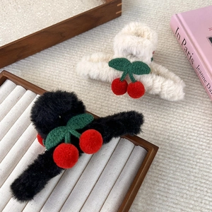 Dettaglio di mollette per capelli a ciliegia in peluche nero e beige con finta pelliccia