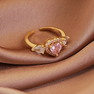Macro shot of gold-plated open ring with pink heart gemstone and zircon details