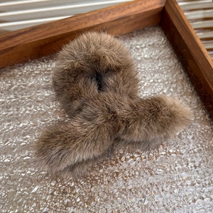 Detail view of a warm brown plush hair claw clip on a textured wooden tray