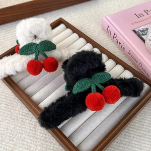 Pinze per capelli carine in peluche ciliegia bianche e nere su un vassoio in legno