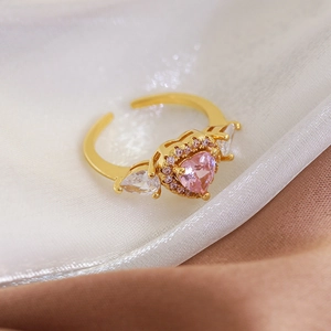 Macro detail of open gold ring featuring a pink heart stone with pavé zircon accents