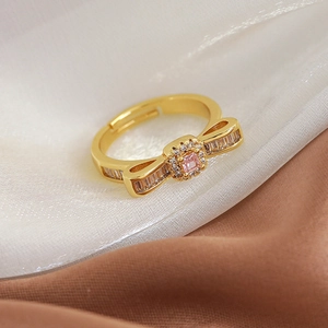 Detailed macro view of gold bow ring with pink center stone and sparkling side zircons