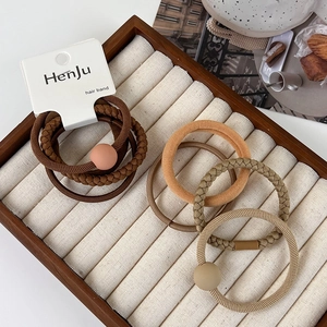 Close-up of minimalist hair ties in earth tones displayed on a white jewelry tray