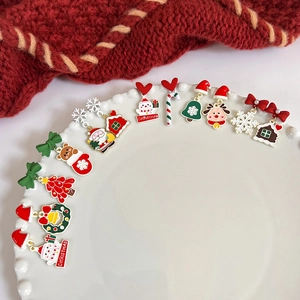 Christmas themed earring set with Santa Claus and snowman motifs on a white ceramic plate