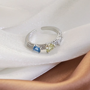 Detailed close-up of a silver open ring featuring micro-pave crystals and colorful gems