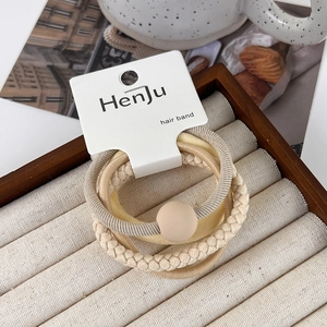 Detail of 4-piece earth-toned hair ties set including woven and beaded styles on a tray