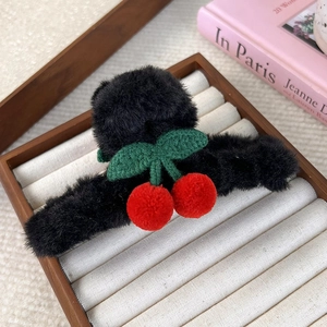 Dettaglio della molletta per capelli in peluche con ciliegie rosse e foglie lavorate