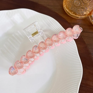 Makro-Detail einer Haarklammer mit glitzernden rosa Herzen auf einem Keramiktablett