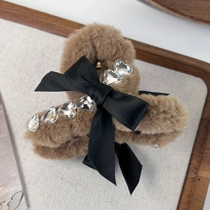 Detailed macro of the brown plush hair claw with a black bow and heart-shaped rhinestones