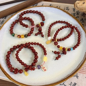 Close-up of cinnabar-style red beaded bracelets with golden fortune pendants on a plate